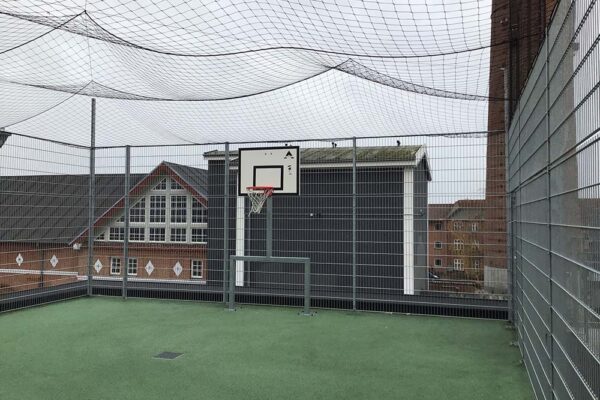 Billede af indhegnet fodboldbane på tag af skole. Der er benyttet panelhegn med nettag.
